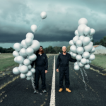 Portrait du duo Chill Bump qui se trouve à l'extérieur sur une route, ils sont côte à côté et tiennent respectivement des ballons gonflables